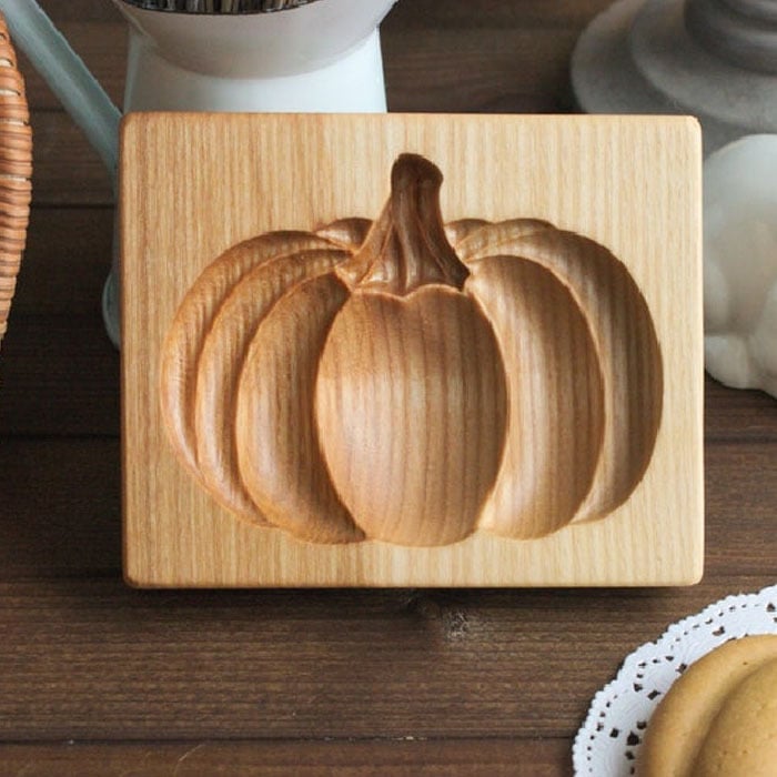 Wooden coaster with pumpkin design on a wooden surface