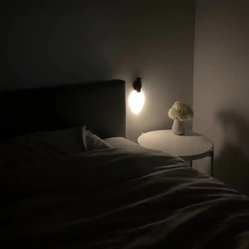 Rechargeable sensor wall light — glowing beside a bed in a dark bedroom setting