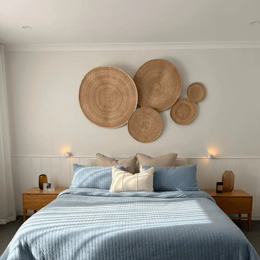 LED rechargeable wall sconce — pair providing ambient light above a blue-linen bed with woven wall art