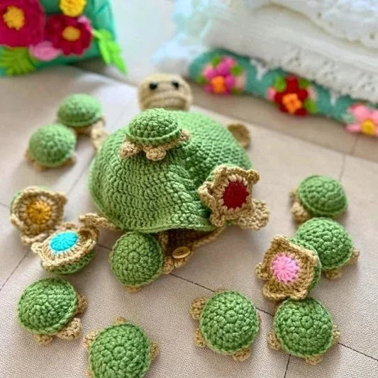Crocheted turtle and turtle eggs on a textured surface with colorful flowers in the background.