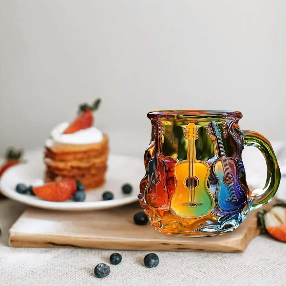 Colorful glass mug with guitar design on a table with a cake and fruit in the background