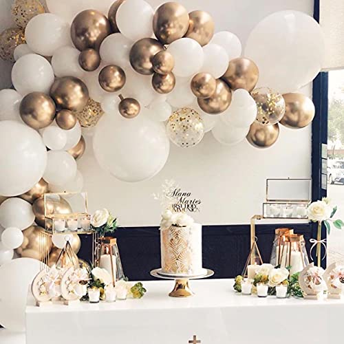 A balloon garland arch kit with white and gold balloons arranged on a wall, with a cake and decorations below.